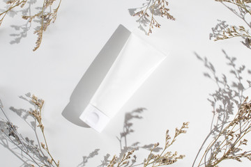 white beauty cream cosmetic tube packaging with cassia flower in sun morning