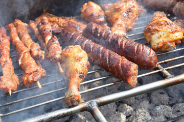 roasted chicken, sausages and skewers on the grill in the smoke