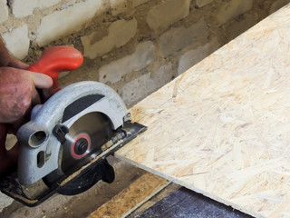 Close up electric saw to sawing wood board.