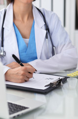 Doctor woman filling up prescription, close-up of hands. Physician at work. Medicine and healthcare concept
