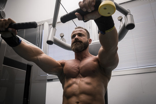 Hombre fuerte con grandes músculos entrenando pecho en el gimnasio. Ponerse en forma.