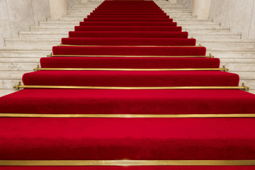 Red carpet on marble stairway welcoming VIPs.