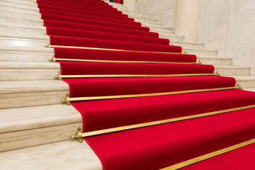 Red carpet on marble stairway welcoming VIPs.