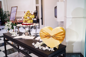 Heart shape box in gold color at the front of wedding reception with sign book