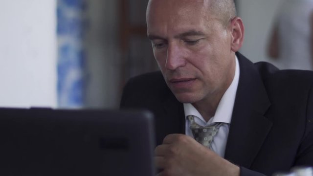 The man at the laptop straightens his tie