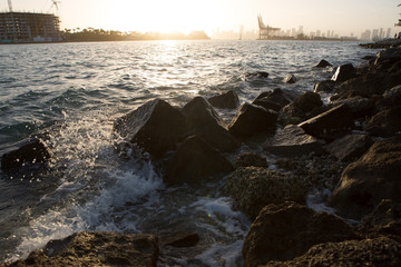 water hitting rocks over coast at sunset