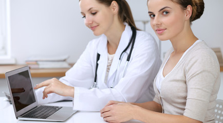 Doctor and patient having a pleasure talk while sitting at the desk at hospital office. Healthcare and medicine concept