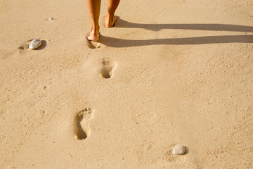 Trail of feet in sand on the sea shore