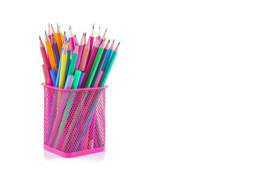 A lot of colored pencils in a pink glass on a white isolated background. School supplies. Stationery.