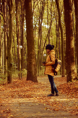 Young stylish hipster girl standing in the autumn park and reading, retro vintage image