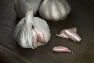 Garlic and garlic cloves close up on dark cutting board