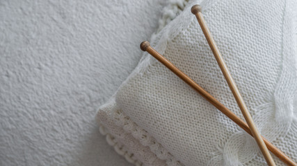 Fototapeta na wymiar White sweaters and yarn for knitting close up. Knitting needles. Concept Handicraft. Place for text
