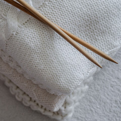 Fototapeta na wymiar White sweaters and yarn for knitting close up. Knitting needles. Concept Handicraft. Place for text