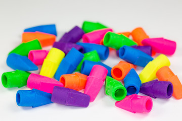 Colorful pencil erasers cluttered on a white surface
