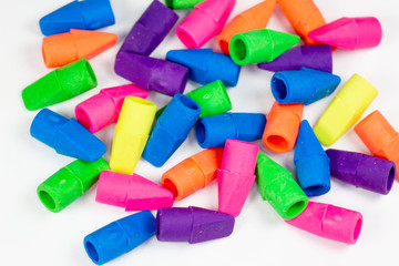 Colorful pencil erasers cluttered on a white surface