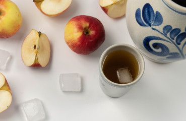 Traditional Frankfurt apple wine in a jug bembel with beaker and apples on white background