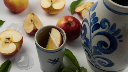 Traditional Frankfurt apple wine in a jug bembel with beaker and apples on white background