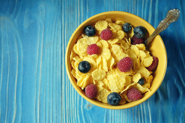 Cornflakes with berries raspberries and blueberries on blue wooden background.