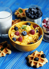 Healthy breakfast. Corn flakes with raspberries and blueberries, granola with yogurt and berries, wafers and milk. A great start to the day.
