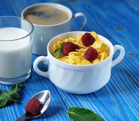 Healthy eating, food and diet concept - Cornflakes with berries, milk and coffee for breakfast. Blue wooden background. Top view.