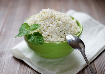 Cottage cheese with mint in a green bowl on a white napkin.