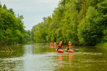 A group of tourists floats on a fresh, calm river on inflatable catamarans, outdoor activities,...
