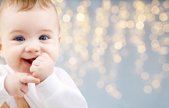 childhood and people concept - close up of sweet little baby over festive lights background
