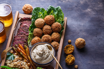 Close view of falafel, babaghanoush and pastrami in the wooden box, copyspace.