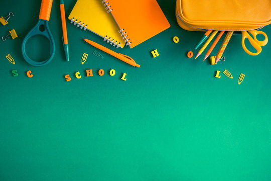 School accessories, pencils, paints, pens on green background. Back to school. Word school, wooden letters. Flat lay, top view, copy space 