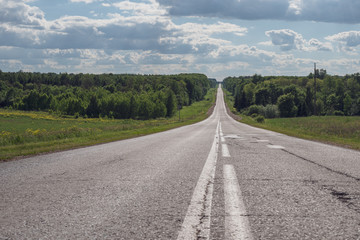 Gray asphalt road with white markings going into the horizon, the concept of life, achieving goals, strong character