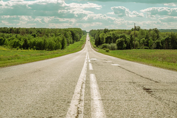 Gray asphalt road with white markings going into the horizon, the concept of life, achieving goals, strong character