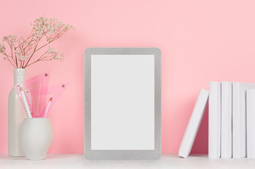 Elegant home workplace with stylish silver blank tablet and white stationery, flowers in vase on pink background.