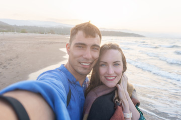 Fototapeta na wymiar Emotional selfie of a young couple on the sea coast at sunset