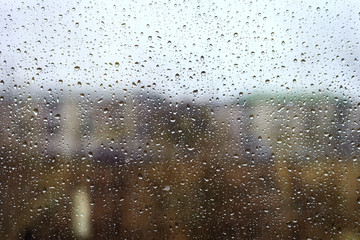 Water drops from rain on the window glass against the urban landscape, tinted
