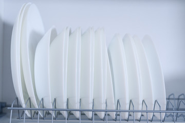 White ceramic plates stacked in a row in a drying locker close-up