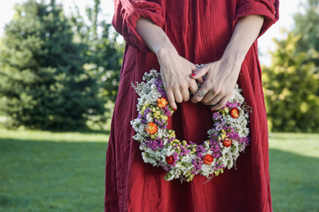Fototapeta na wymiar Woman in red dress holding beautiful flower wreath 