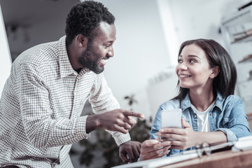 What is this. Delighted positive curious man looking at his friend and pointing at the screen while asking what is shown on it