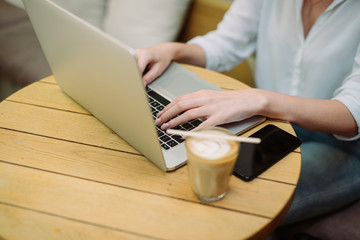 Fototapeta na wymiar Woman using a laptop during a coffee break, hands close up