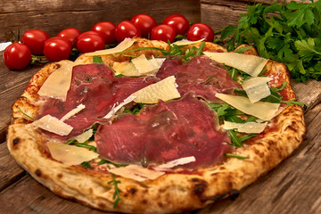 Homemade fresh delicious gourmet pizza whit carpaccio matured beef, rocket and slices of grana...