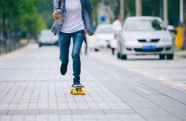woman skateboarding with coffee cup in hand on city street