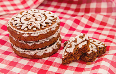 pile of gingerbreads with two broken pieces on red and white tradational tablecloth