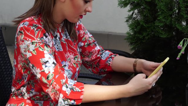 Beautiful girl in red dress, with flower pattern on the terace, outdoor in business centr.