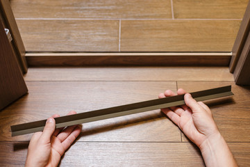 Repair, building and home concept. Construction worker fixing metal profile to the doorstep with...