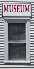 Obraz premium Red-lettered MUSEUM sign attached to exterior white building wall above window.