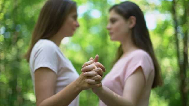 Lesbians holding hands firmly and kissing, support despite society condemnation