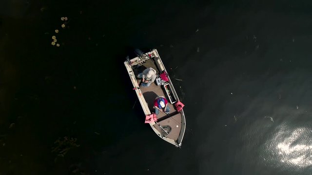 Overhead rotating aerial slow motion footage of a father and son fishing in a boat on a lake. Filmed in 4k UHD (3840 x 2160) at 59.94 fps and conformed to 23.976 fps.