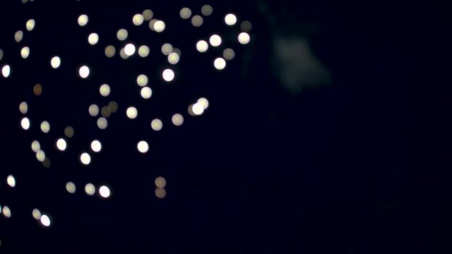 Out of Focus Firework Exploding and Glittering Across the Sky.  Shot on a Blackmagic Ursa Mini Pro 4.6k with a Sigma 50-100mm f/1.8.