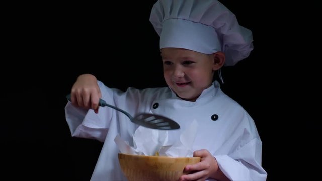 Little chef with bowl of french fries on the black background