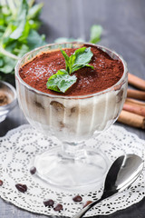 Italian dessert tiramisu in glass on dark wooden background, sweet food. Top view