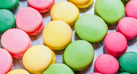 Fototapeta na wymiar Colorful tasty macaroons on wooden table with flowers, a french sweet delicacy, macaroon texture. Top view, flat lay.